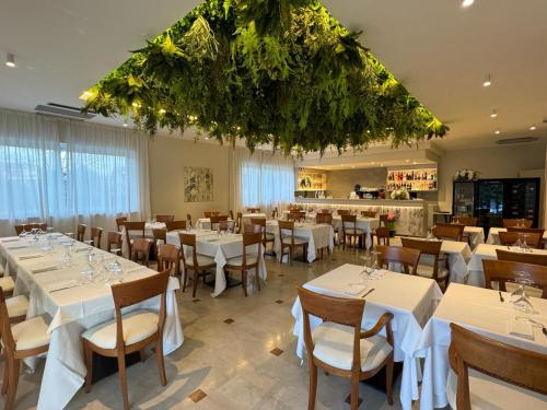 una sala da pranzo con tavoli e sedie bianchi di Hotel Dorè a Castelnuovo del Garda
