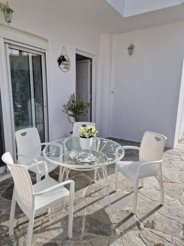 a glass table with white chairs and a glass table and chairs at Seva's House in Psinthos