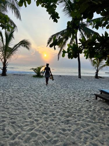 a person walking on the beach with a surfboard at Diani Sun Beachfront Studio in Ukunda