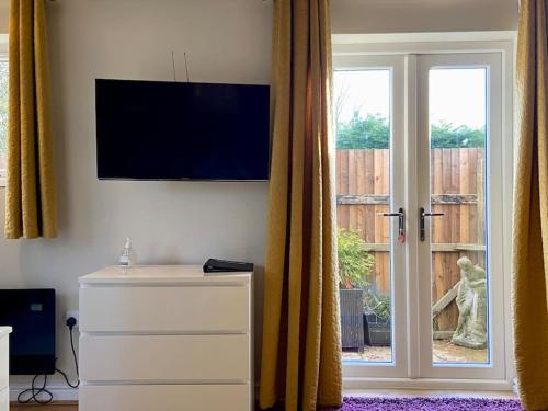 a living room with a tv and a sliding glass door at Southdene Studio in Lincoln