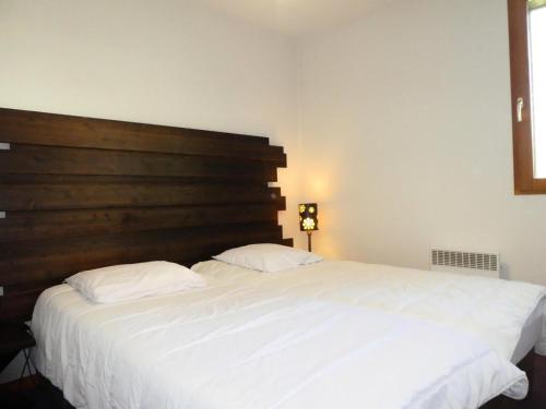 - une chambre avec un grand lit blanc et une tête de lit en bois dans l'établissement Résidence Les Fermes De Saint Gervais - Fermes de Saint Gervais A7 MAE-5287, à Saint-Gervais-les-Bains