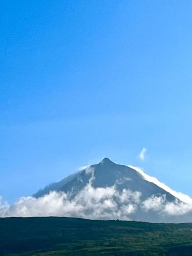 a mountain covered in clouds with a blue sky at Casa da Olivia in Lajes do Pico
