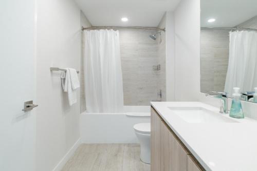 a white bathroom with a toilet and a sink at Desing district, great apartment in Miami