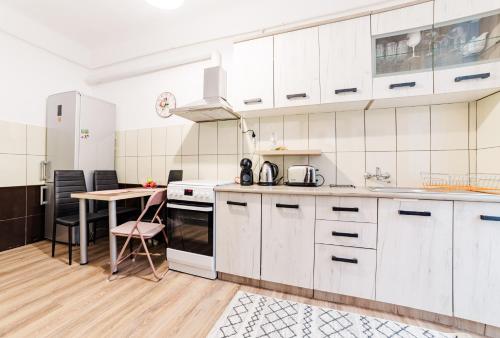 a kitchen with white cabinets and a table at ALBERT RESIDENCE Aparthotel in Braşov