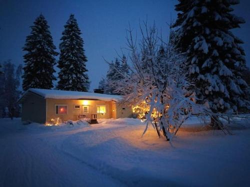 a house with christmas lights in the snow at night at Omakotitalo Simojärvellä in Ranua