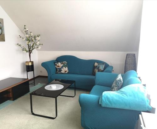 uma sala de estar com um sofá azul e uma mesa em Ferienwohnung Jasmin - a53959 em Maasholm-Bad