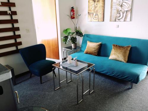 uma sala de estar com um sofá azul e duas cadeiras em Ferienwohnung Jasmin - a53959 em Maasholm-Bad