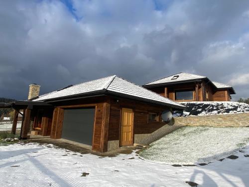 una casa de madera con garaje en la nieve en Bielańska Ostoja en Uście Gorlickie