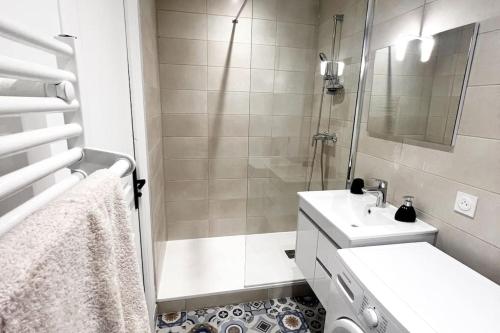 une salle de bain blanche avec une douche et un lavabo dans l'établissement Appartement spacieux chaleureux, à Roanne