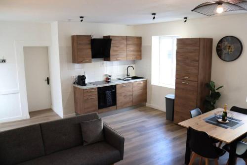 un salon avec un canapé et une table et une cuisine dans l'établissement Appartement spacieux chaleureux, à Roanne