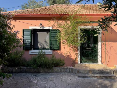 Cette petite maison dispose d'une fenêtre et de volets verts. dans l'établissement Cozy Anthousa House with Sea View, à Anthoúsa