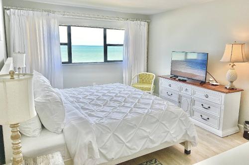 a white bedroom with a bed and a window at Ocean Breeze Condo in Jensen Beach