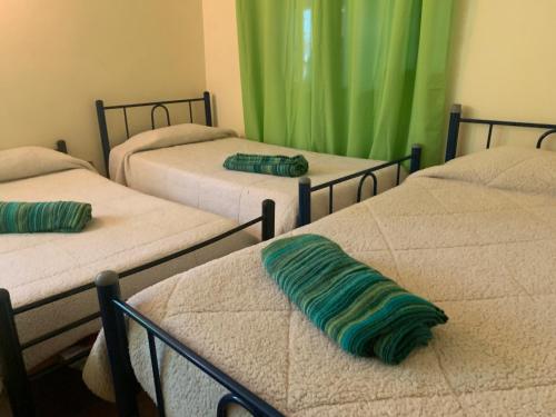 three beds in a room with green curtains at RESIDENCIAL ESMERALDA in Quilpué
