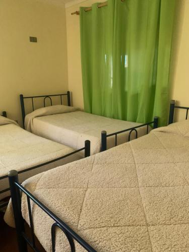 three beds in a room with green curtains at RESIDENCIAL ESMERALDA in Quilpué