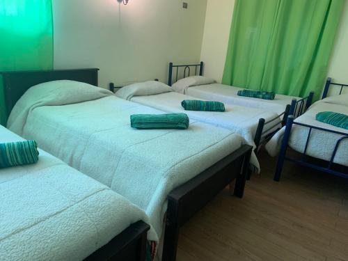 a group of four beds in a room with green curtains at RESIDENCIAL ESMERALDA in Quilpué