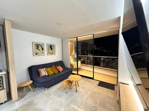 a living room with a blue couch and a large window at Aluna Apto/ Wellness and Enjoy in Sabaneta