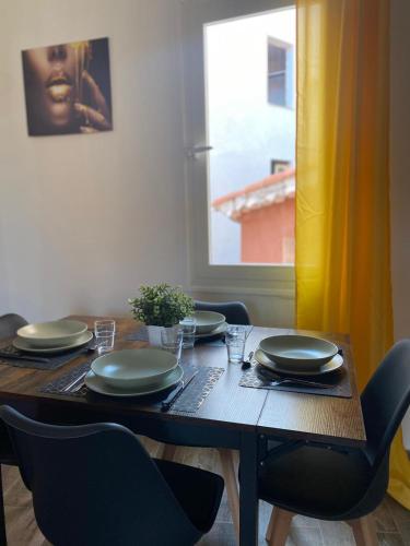 - une table à manger avec des chaises et des assiettes dans l'établissement Appartement Cœur de Grasse, à Grasse