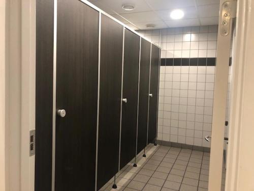 a row of stalls in a bathroom with black doors at Motel eat´n drive Padborg in Padborg