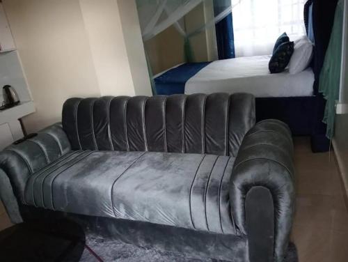 a living room with a leather couch and a bed at Legacy Stays in Kikuyu