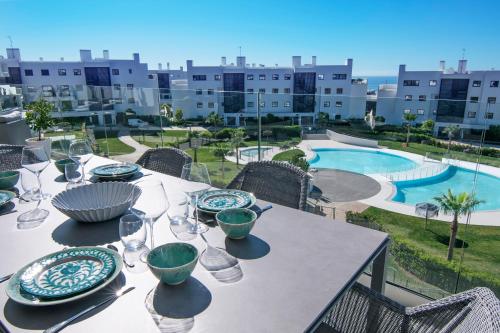 a table with plates and wine glasses on a balcony at Mara's Apartments Higuerón West - Luxurious & Sunny in Fuengirola