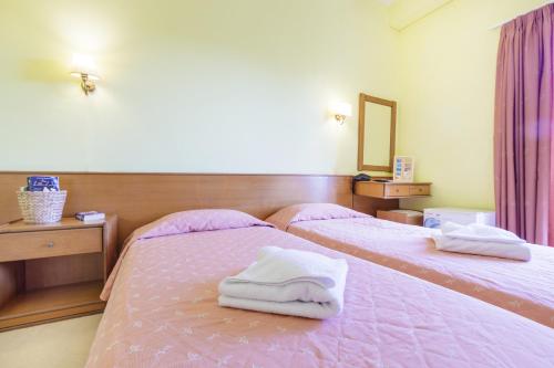 two beds in a room with towels on them at CiTYZen Hotel in Loutraki