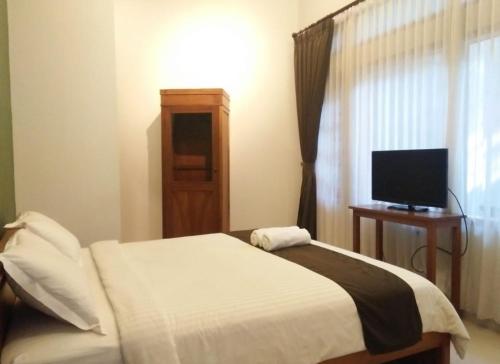 a bedroom with a bed with a television and a window at Helena Guest House in Rampal