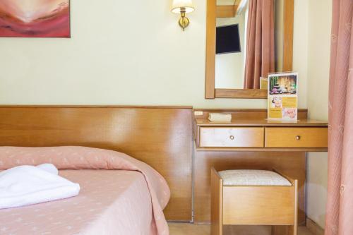 a bedroom with a bed and a desk with a mirror at CiTYZen Hotel in Loutraki