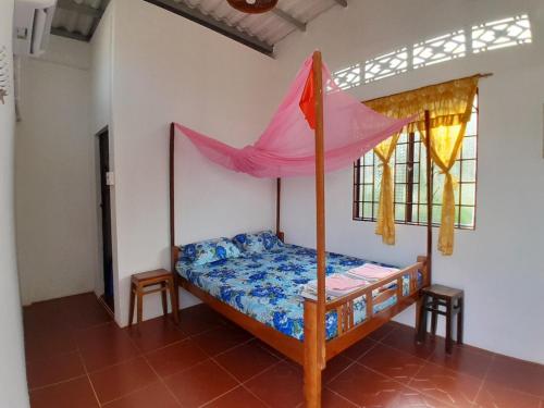 1 dormitorio con 1 cama con sombrilla rosa en Happy Family Guesthouse en Vĩnh Long