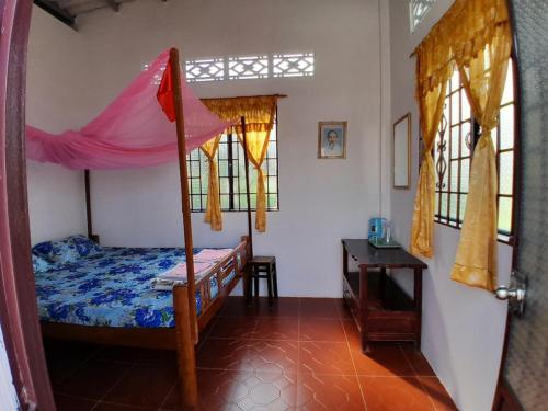 a bedroom with a bed with a canopy and windows at Happy Family Guesthouse in Vĩnh Long