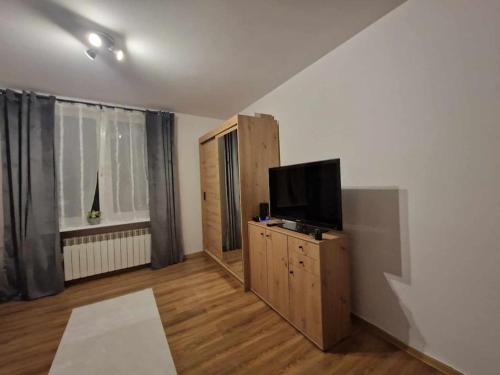 a living room with a flat screen tv on a wooden cabinet at Mieszkanie na doby dla dwojga in Kraśnik