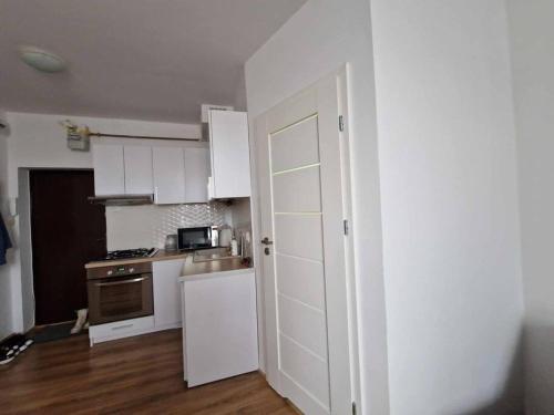 a kitchen with white cabinets and a white door at Mieszkanie na doby dla dwojga in Kraśnik