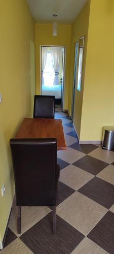 Zimmer mit einem Tisch, einem Stuhl und einem Schachbrettboden in der Unterkunft Apartmani Ad fines in Kuršumlija