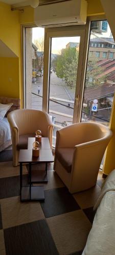 Zimmer mit 2 Stühlen, einem Tisch und einem Fenster in der Unterkunft Apartmani Ad fines in Kuršumlija