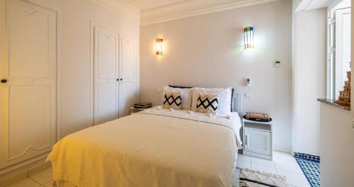 a white bedroom with a bed and a window at Charming 2-Bed Oasis Pool View in Marrakech