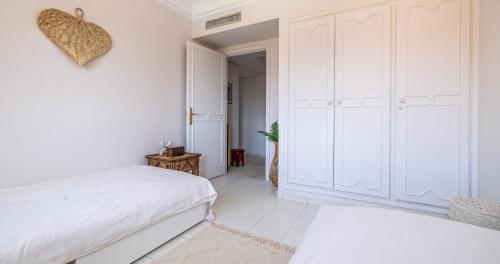 a white bedroom with a bed and a closet at Charming 2-Bed Oasis Pool View in Marrakech