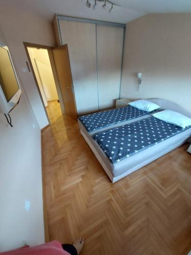 a large bed in a room with a wooden floor at Index Apartman in Banja Luka