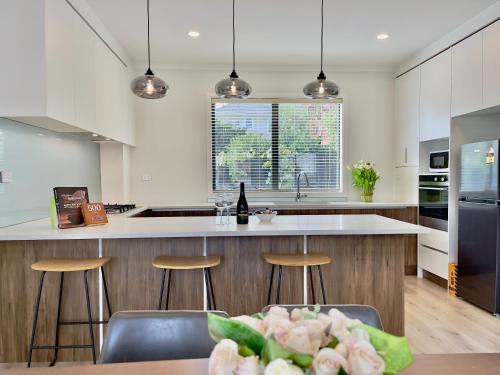 uma cozinha com uma grande ilha com bancos de bar em Glendowie Brand-new comfortable 3 & 4-bedroom Houses em Auckland