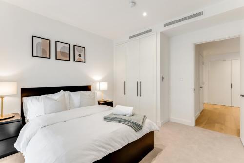 a white bedroom with a large bed and two lamps at Khayat Homes - The Ostrich - One Bed Luxury Apt in London
