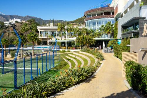 a walkway next to a building with a tennis court at Mara's Apartments Higuerón West - Luxurious & Sunny in Fuengirola