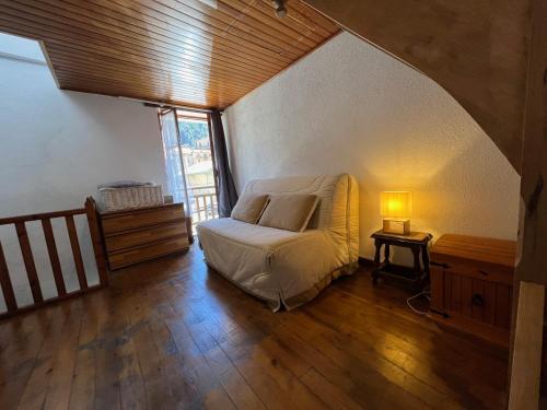 - une chambre avec un lit et une lampe sur du parquet dans l'établissement T2 pour 4 personnes au cœur de St Martin Vesubie avec parking public devant, à Saint-Martin-Vésubie