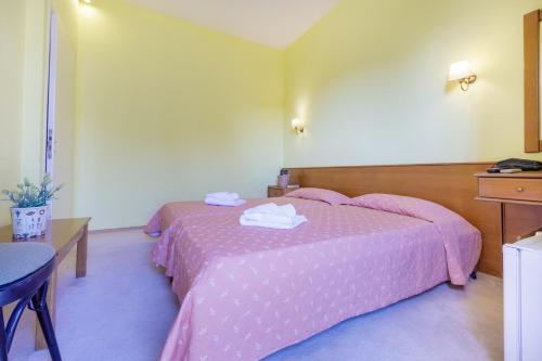 a bedroom with a pink bed with a table and a desk at CiTYZen Hotel in Loutraki