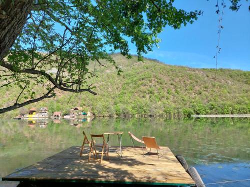 two chairs and a table on a dock in the water at "Kod dva kestena"Warm and cozy house with lake view sauna in Međuvršje