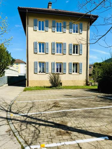 ein großes Gebäude mit blauen Fenstern auf einer Straße in der Unterkunft Appartement in Couvet