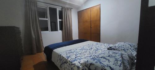 Schlafzimmer mit einem Bett mit einer blauen und weißen Bettdecke in der Unterkunft Disfruta San Antonio en Cali in Cali