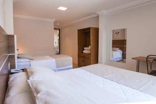 a hotel room with two beds and a desk at Hotel Serra Everest in Nova Friburgo