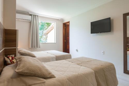 a bedroom with two beds and a television on the wall at Hotel Serra Everest in Nova Friburgo