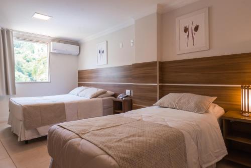 a hotel room with two beds and a window at Hotel Serra Everest in Nova Friburgo