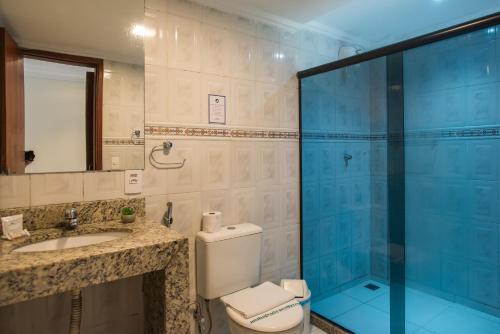 a bathroom with a toilet and a glass shower at Hotel Serra Everest in Nova Friburgo