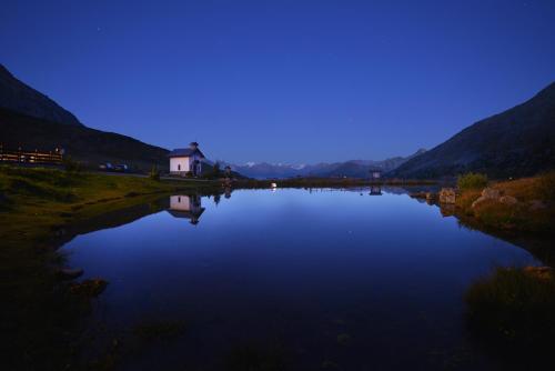 a large lake with a house in the middle at Hotel Interalpen in Valdidentro