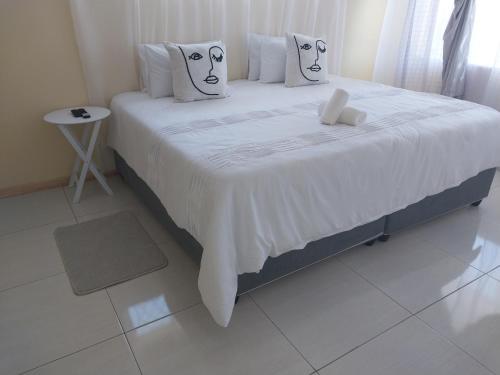 a bedroom with a large bed with white sheets and pillows at Sweet home guesthouse in Mthatha
